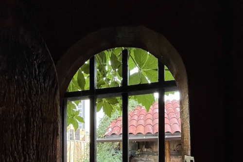 Arched window with bars in a stone wall looking outside